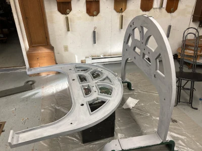Two cast-iron dial frames in grey primer standing on the shop floor, glazing bars visible.